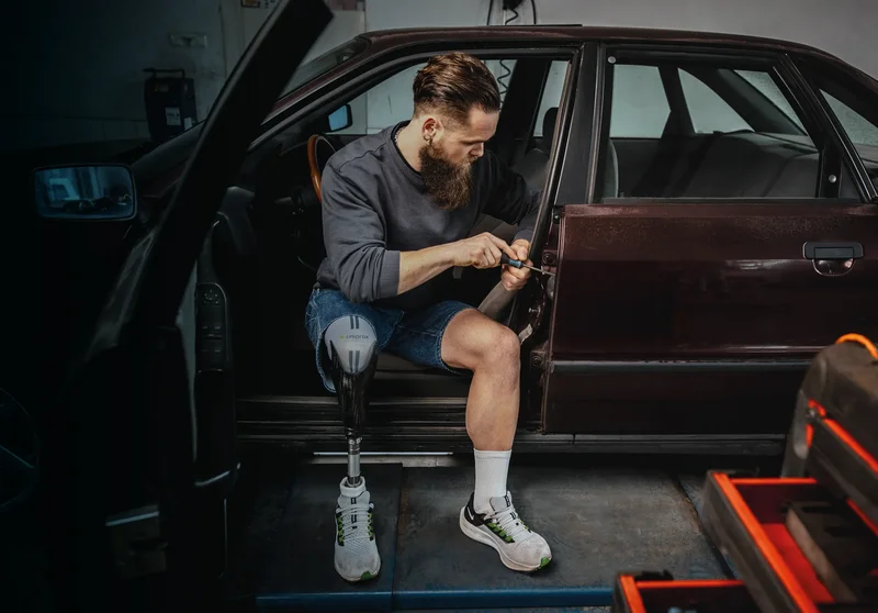 Mann mit Beinprothese und SoftskinAir Liner beim Training am Auto – komfortabler Prothesenliner für Alltag und Aktivität
